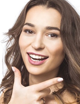 Smiling woman showing off her dental bridge in Dallas