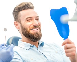 Man admiring smile after replace missing teeth in Dallas