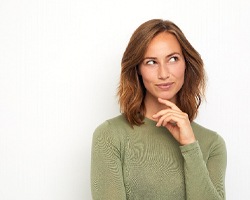 a woman thinking about dental bridges in Dallas