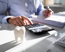 Dentist with calculator estimating cost of dental implants in Dallas, GA
