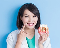 dentist holding model of dental implants in Dallas, GA