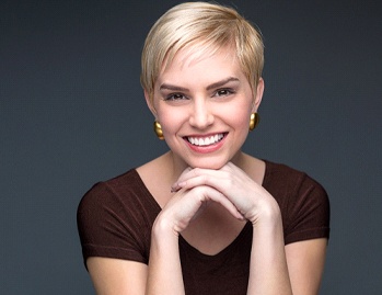 A young woman wearing a brown blouse and smiling after undergoing gum recontouring