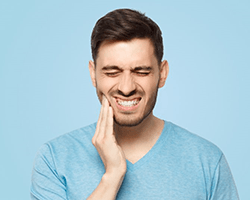 a man touching his jaw due to failed dental implant