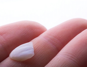 Close-up of hand holding a single veneer in Dallas, TX