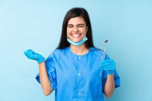 a dental assistant smiling and holding dental instruments