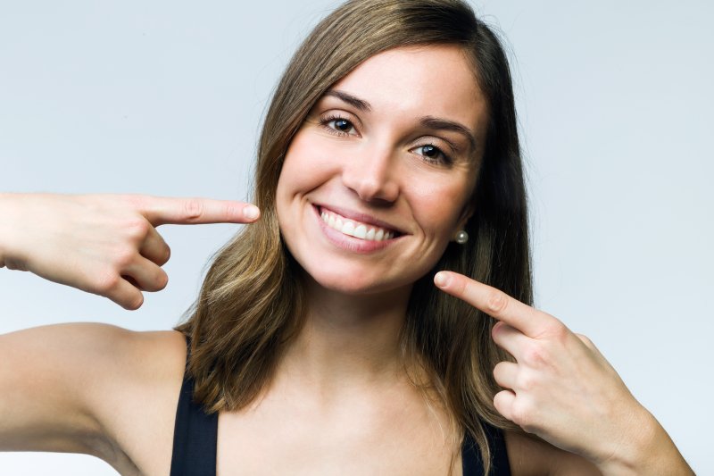 young woman pointing to her smile