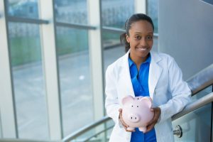 dentist in Dallas, GA smiling and holding a pink piggy bank 