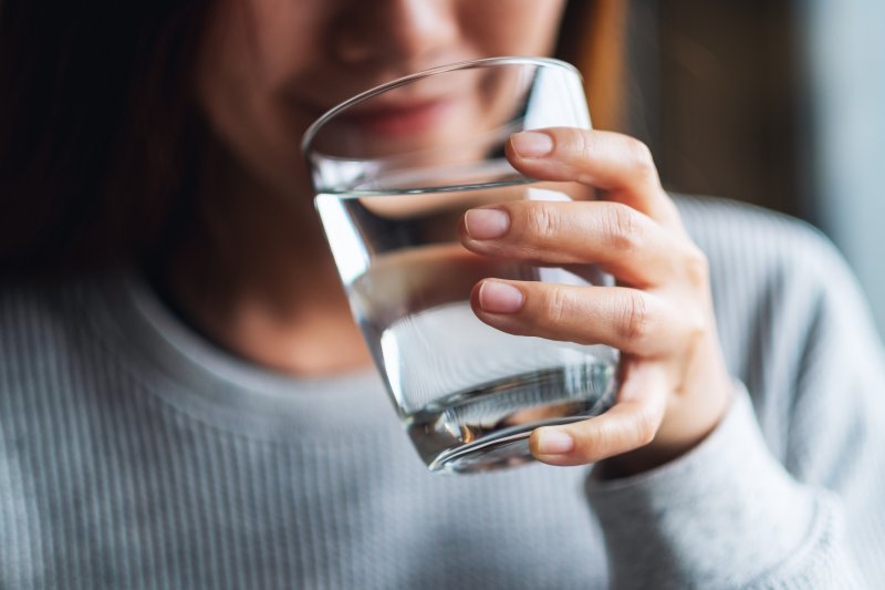 person drinking a glass of water with fluoride in it