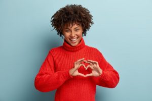 a woman smiling and using her hands to form a heart