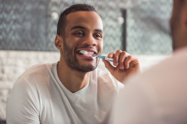 person brushing their teeth in the mirror