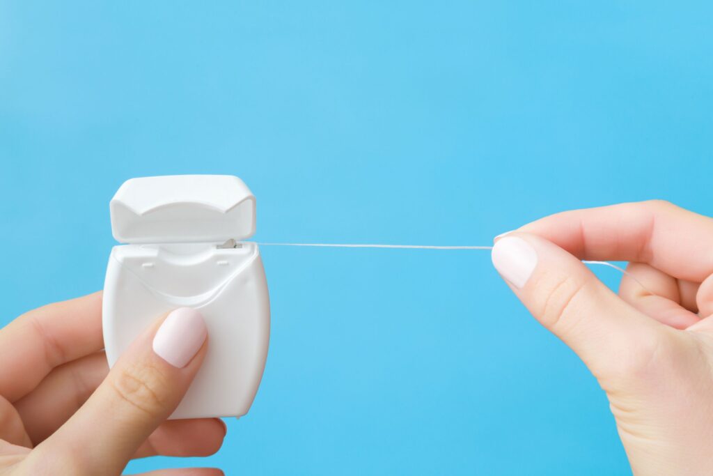 Fingers pullling string floss with blue background