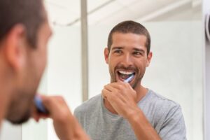Man smiling and brushing his teeth