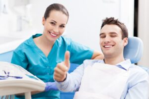 Patient and dentist both smiling with patient giving thumbs-up.